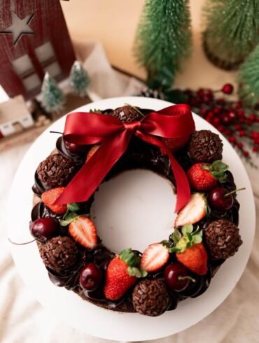 Guirlanda de chocolate com brigadeiros, morangos, cerejas e laço vermelho