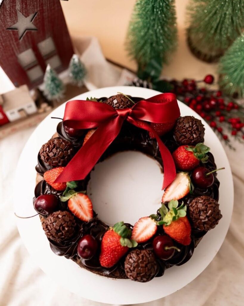 Guirlanda de chocolate com brigadeiros, morangos, cerejas e laço vermelho