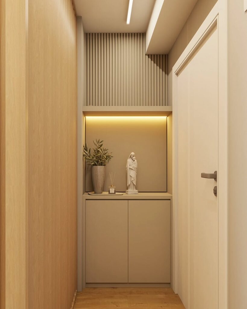 Hall de entrada de apartamento em cores claras, com balcão, luz embutida, vaso de plantas e imagem religiosa