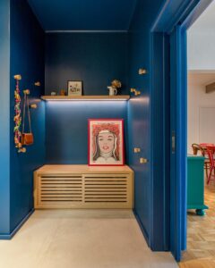 Hall de entrada com parede azul, quadro e prateleira