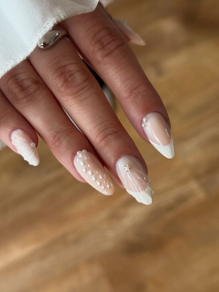 Mão de pele branca com esmalte branco com ténica nail art de sea nails ou mermaid nails para o Ano-Novo
