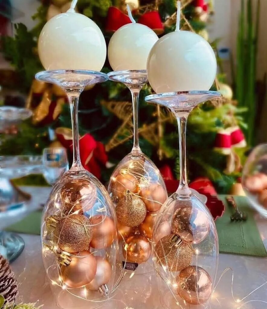 Taças com bolinhas de Natal rosé viradas para baixo com velas em cima