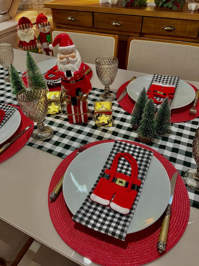 Mesa posta de Natal com caminho de mesa e guardanapos xadrez em branco, preto e cinza, mini árvores e Papai Noel