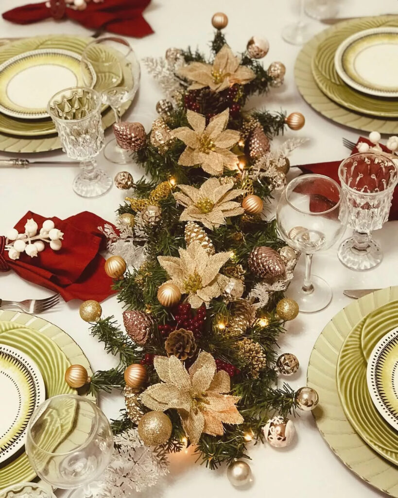 Mesa de Natal com toalha branca, centro com pinhas, flores e bolas douradas