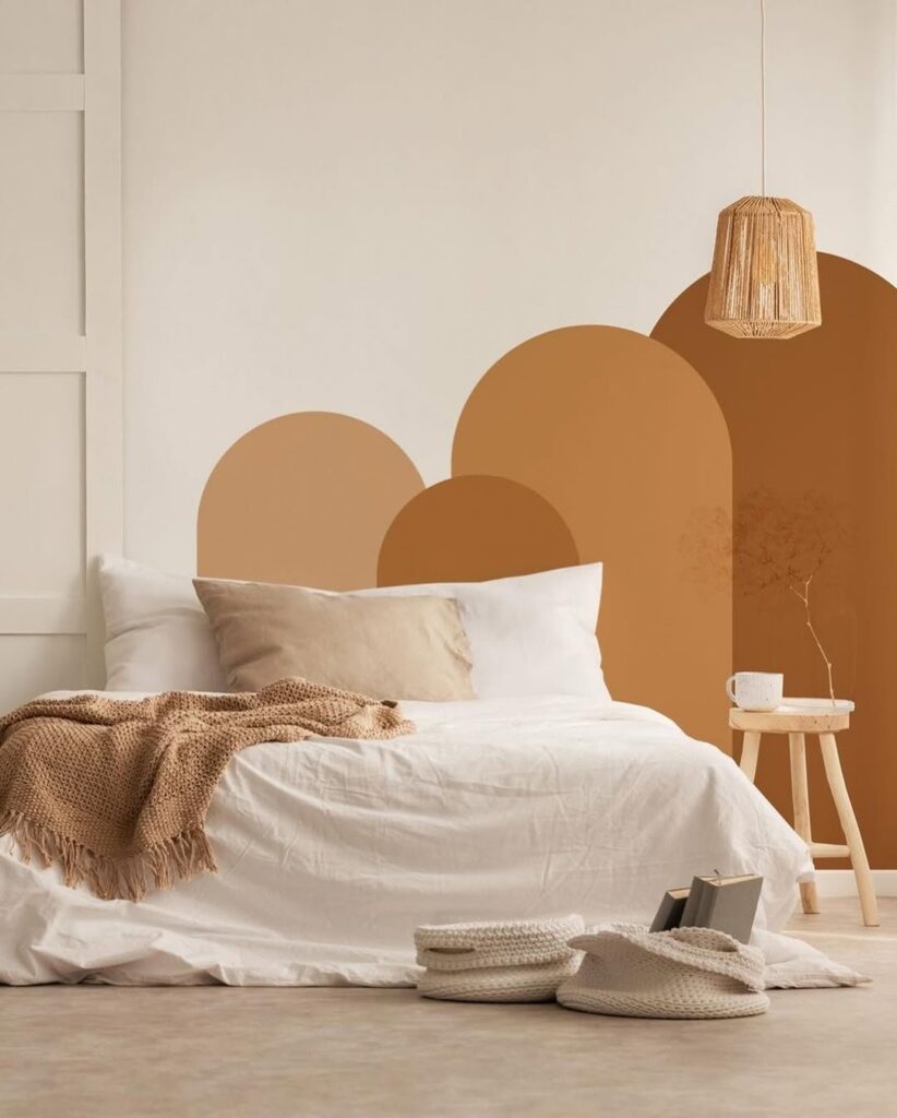 Quarto com cama de casal e mural artístico em tons terrosos