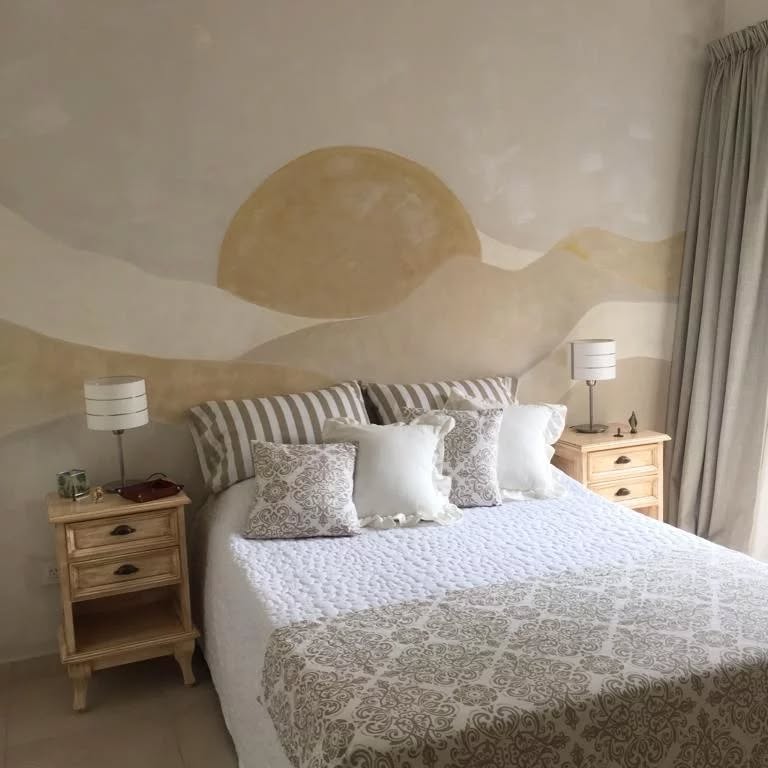 Quarto em tons neutros e mural artístico na parede com montanhas e sol