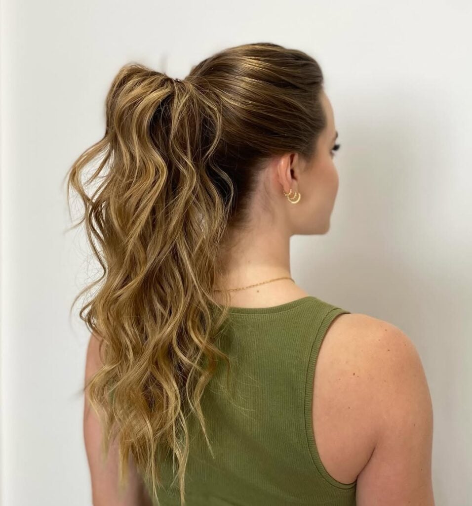 Mulher de pele clara, com blusa verde e cabelo loiro em rabo alto