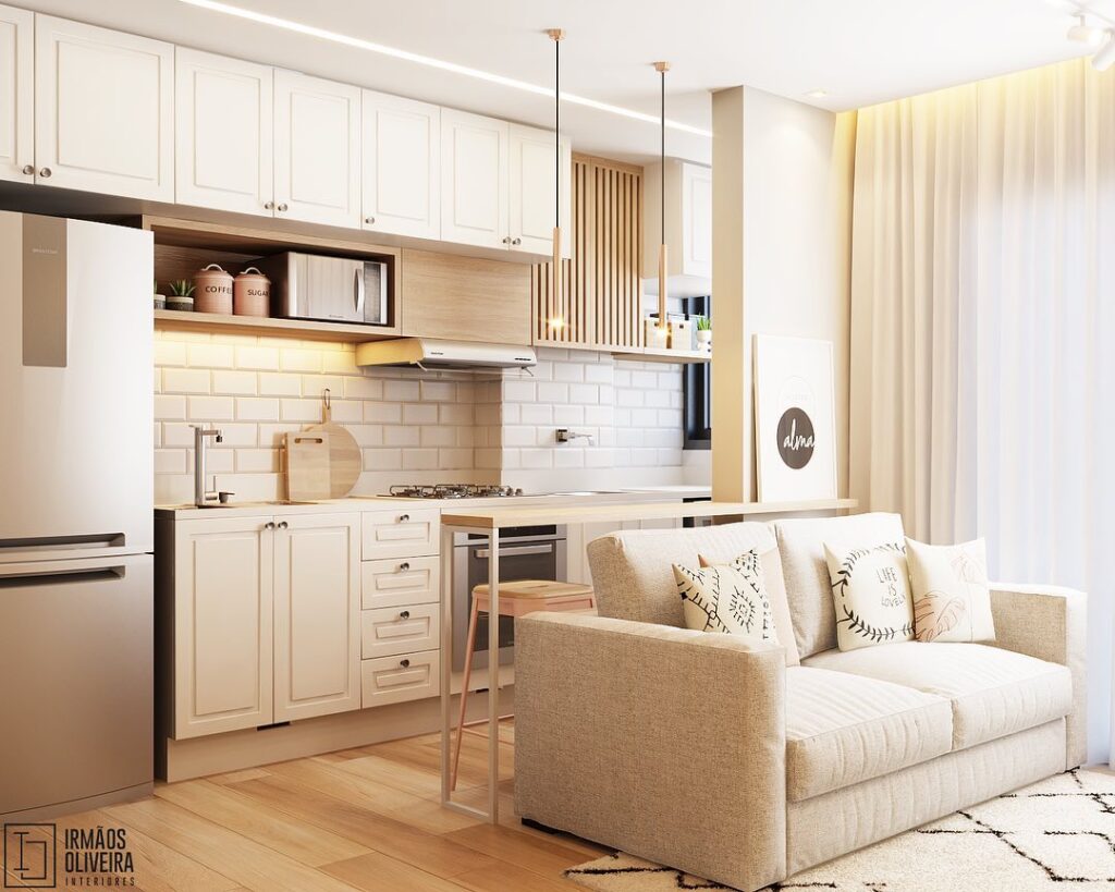 Cozinha com armários off-white, bancada de madeira com pendentes e sofá bege com almofadas