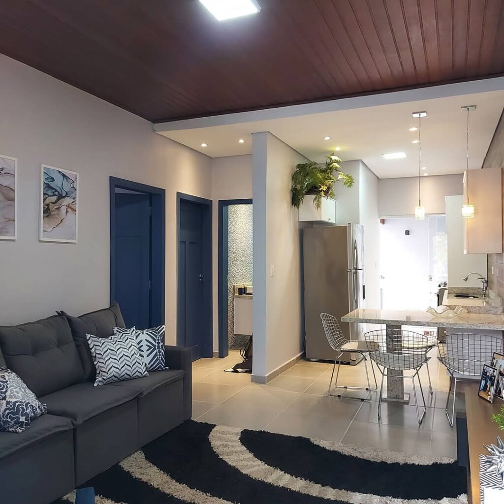 Sala e cozinha conjugadas, sofá cinza e tapete em duas cores