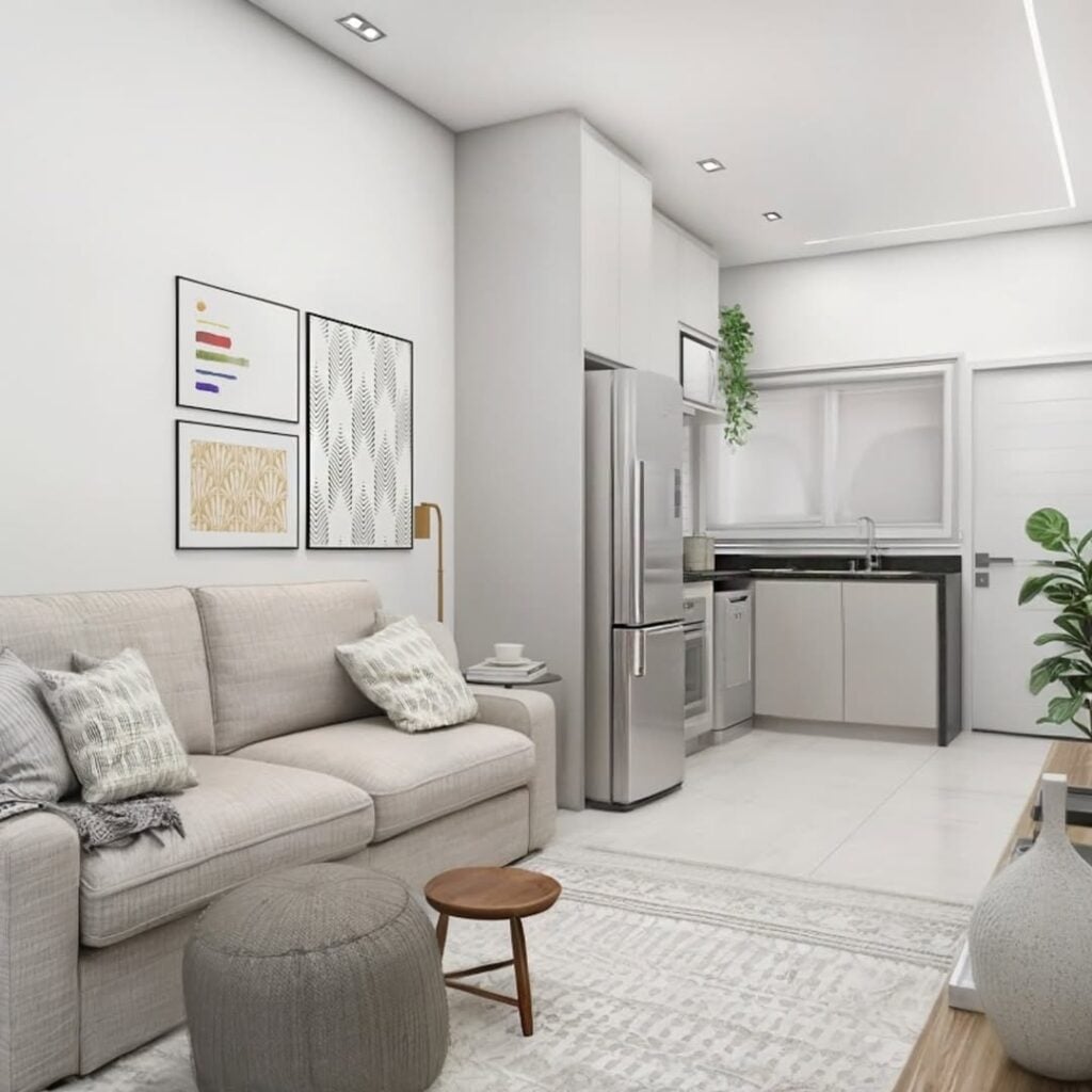 Sala e cozinha em tons neutros, quadros na parede e almofadas no sofá