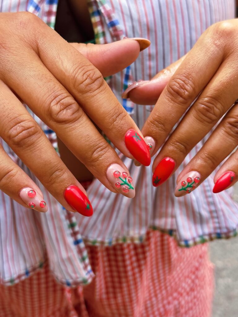 Mão negra com unhas tomato nails com vermelho tomate