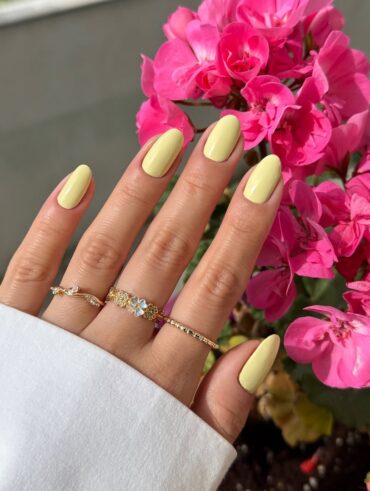 Mão de pele clara, com anéis e unha amendoada amarelo-manteiga