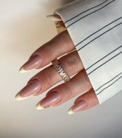 Mão de pele branca com esmalte amarelo-manteiga