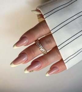 Mão de pele branca com esmalte amarelo-manteiga