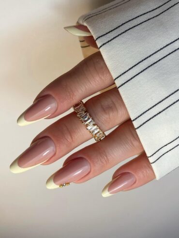 Mão de pele branca com esmalte amarelo-manteiga