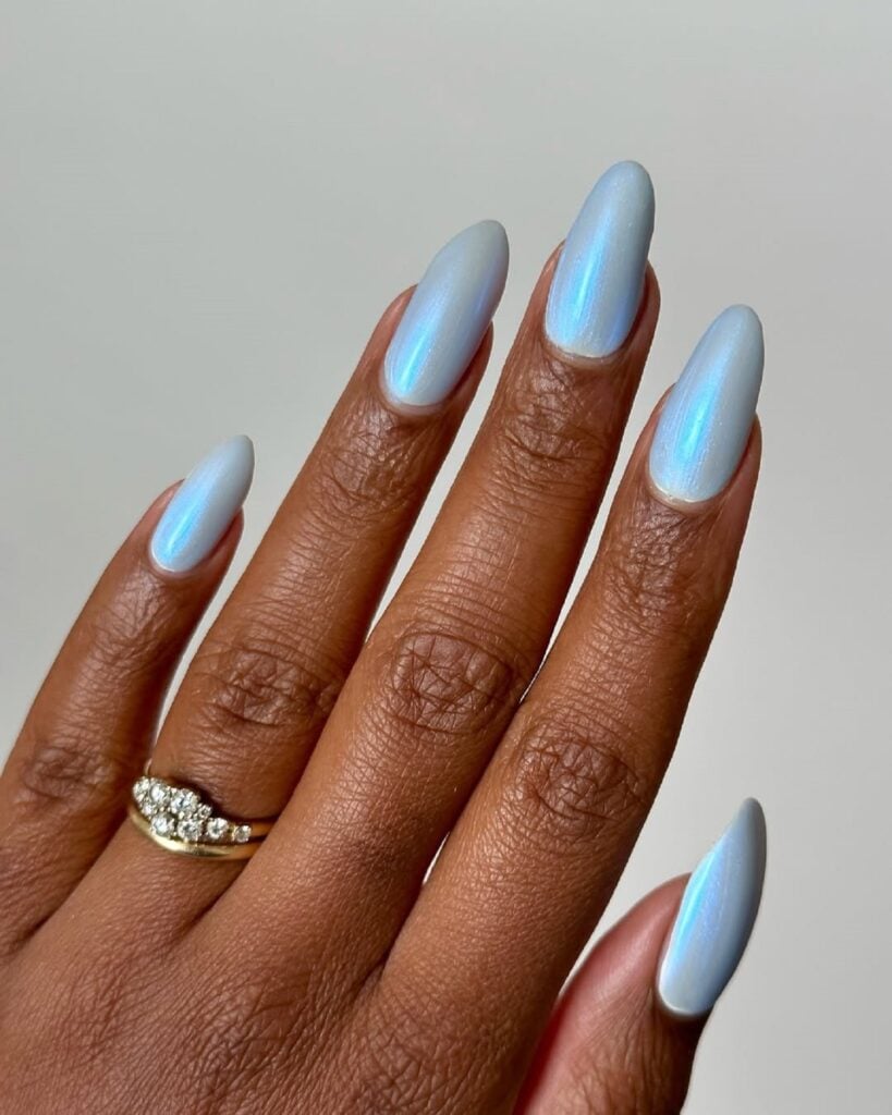 Mão de pele negra com unha tamanho longo e formato amendoado com esmalte azul claro cintilante perolado