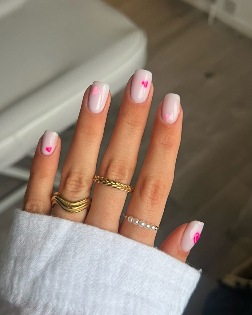 Mão de pele branca com esmalte branco com nail art de coração
