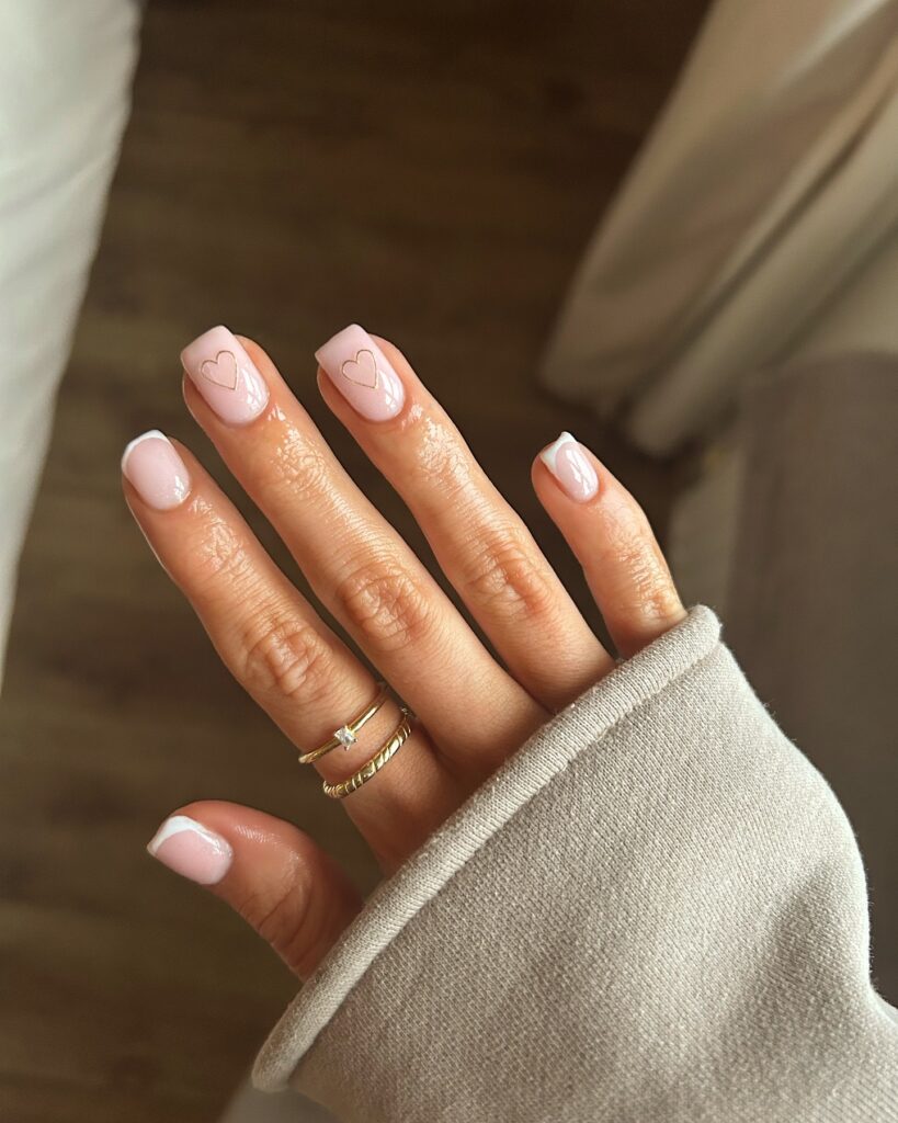 Mão de pele branca com esmalte branco com nail art de coração