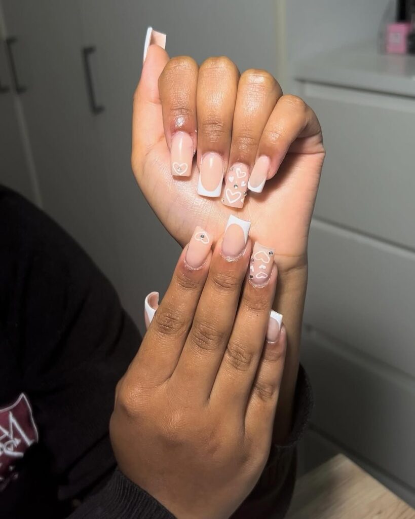 Mão de pele negra com esmalte branco com nail art de coração