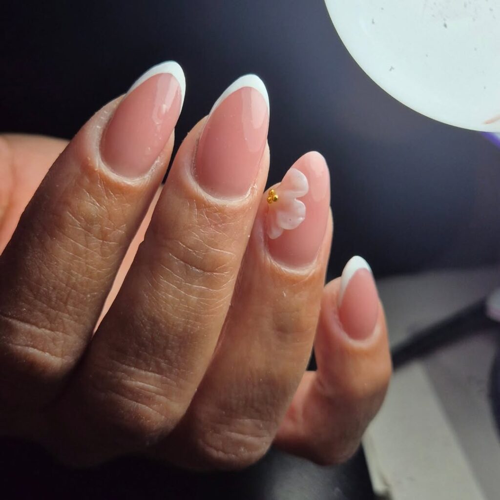 Mão de pele branca com esmalte branco com nail art de charms e esmaltação 3D de flores