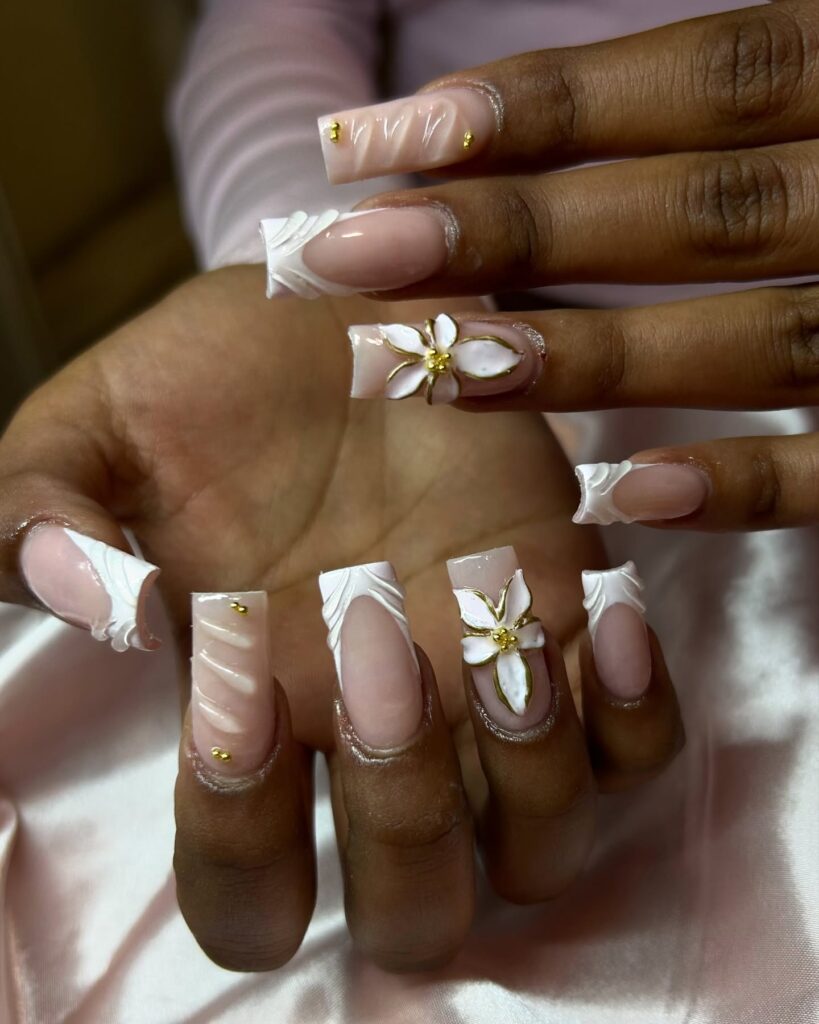 Mão de pele negra com esmalte branco com nail art de charms e esmaltação 3D de flores