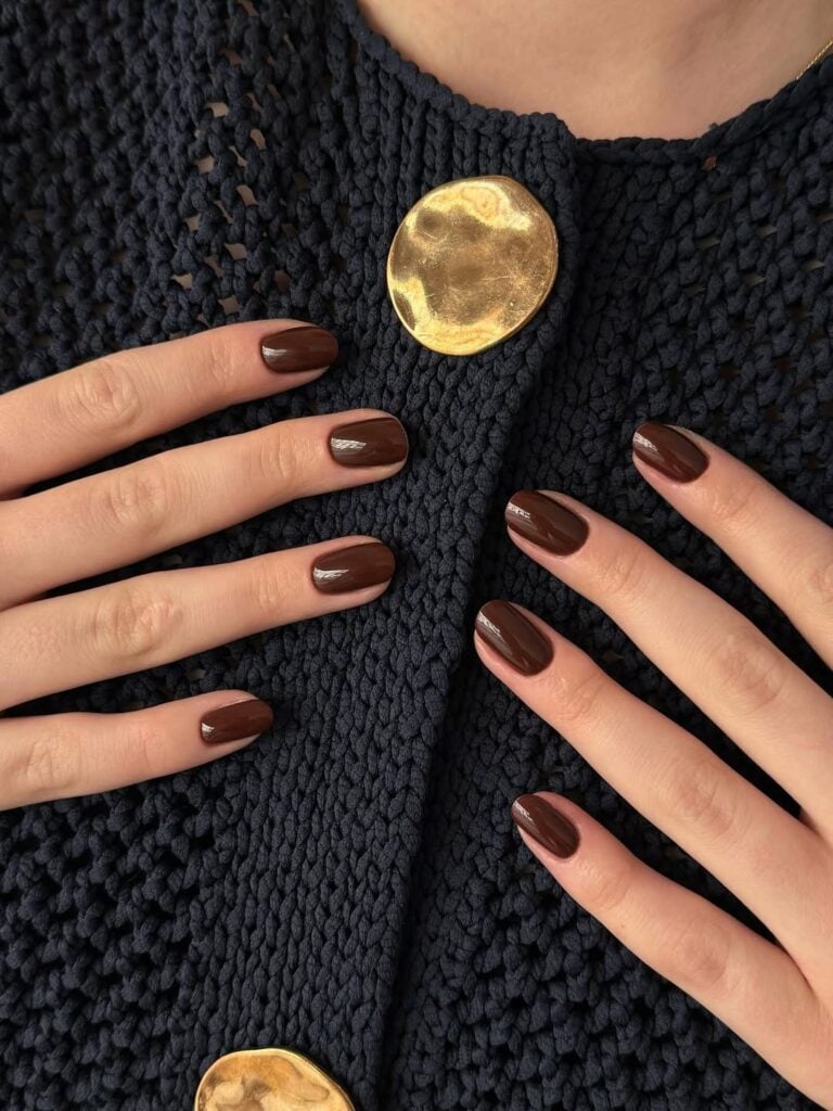 Mãos de pele clara, com unhas chiques curtas e squoval marrom