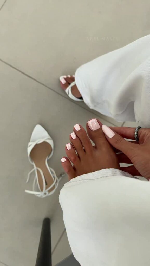 Pés de pele clara, com unhas rosa-claro com acabamento cromado 