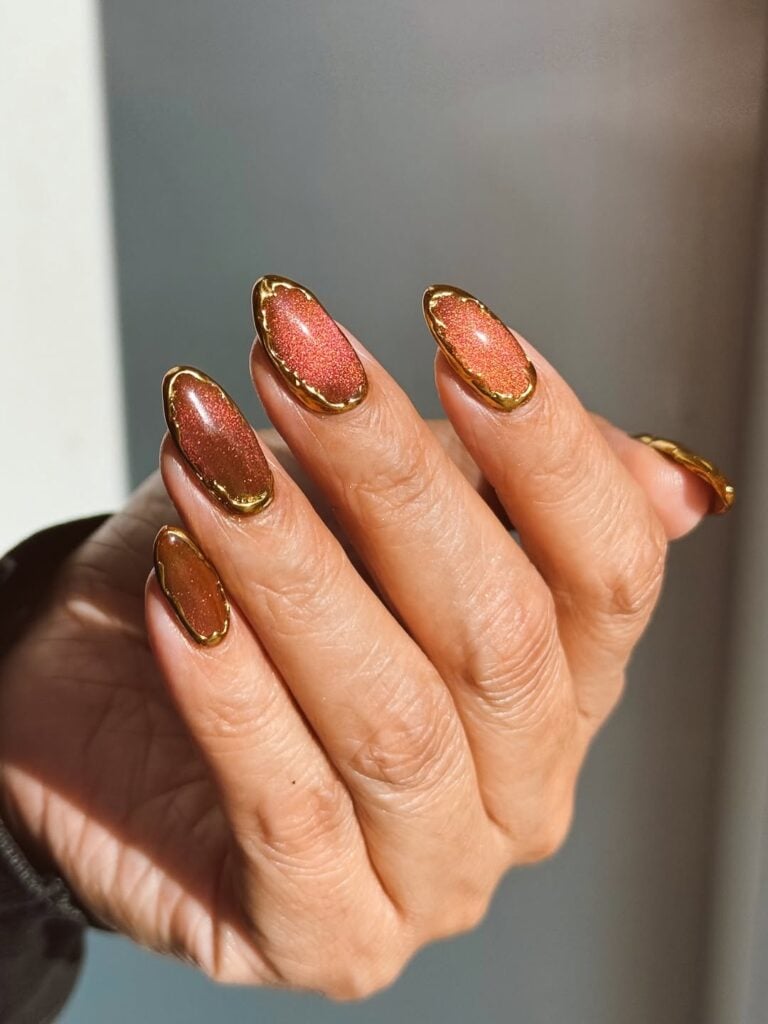 Mão de pele clara, com unha pintada com esmalte magnético e decorada com dourado 