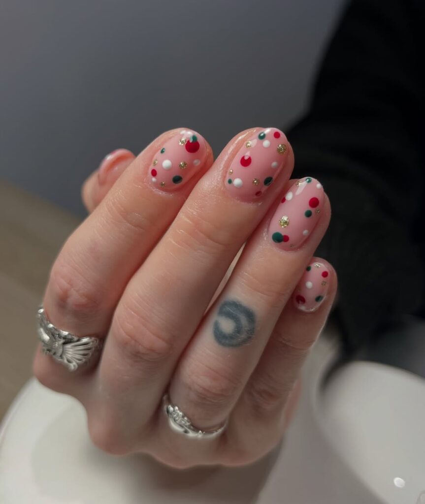 Mão de pele clara, com tatuagens e anéis em prata e unha amendoada com poá 