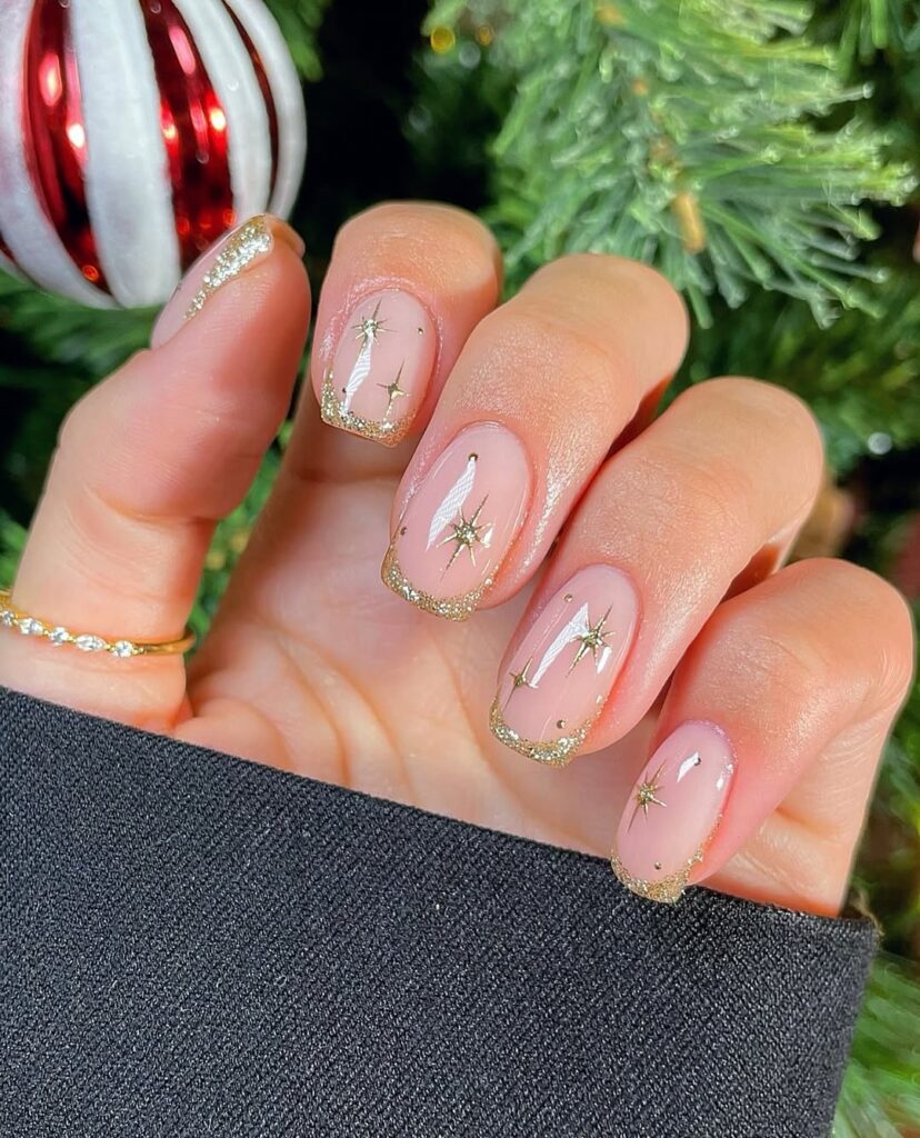 Mão de pele clara, com anel em dourado e unha squoval neutra com decorações em dourado