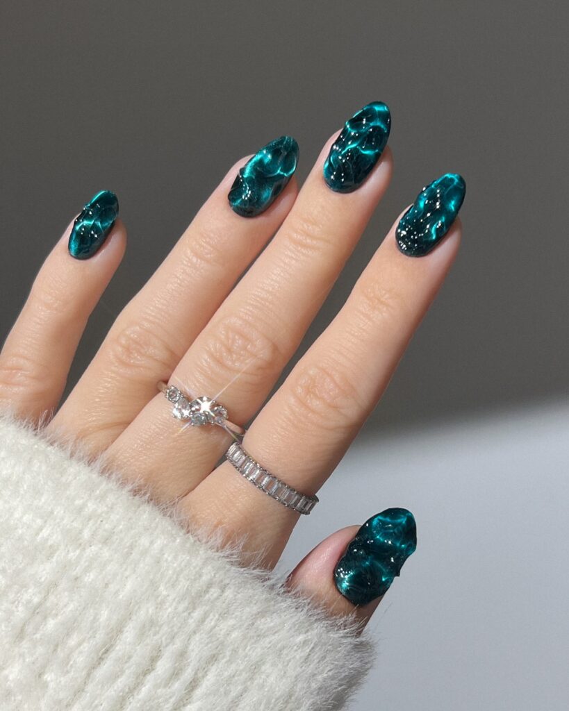 Mão branca com unhas na cor transformative teal com verde e azul é inspiração entre as unhas do verão 2026