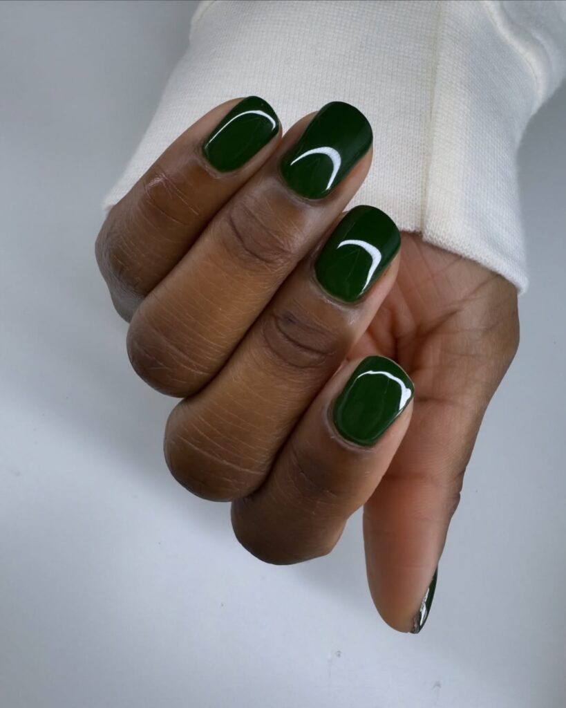Mão de pele preta, com unha squoval verde-escuro 