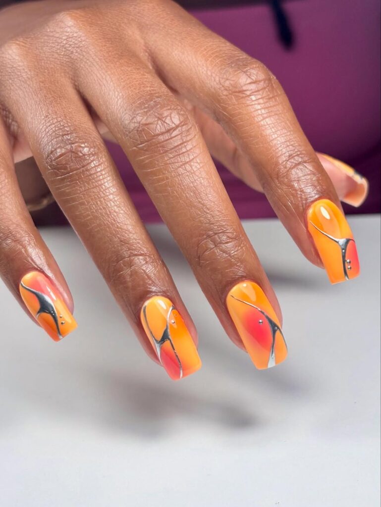 Mão de pele preta, com unha quadrada laranja decorada
