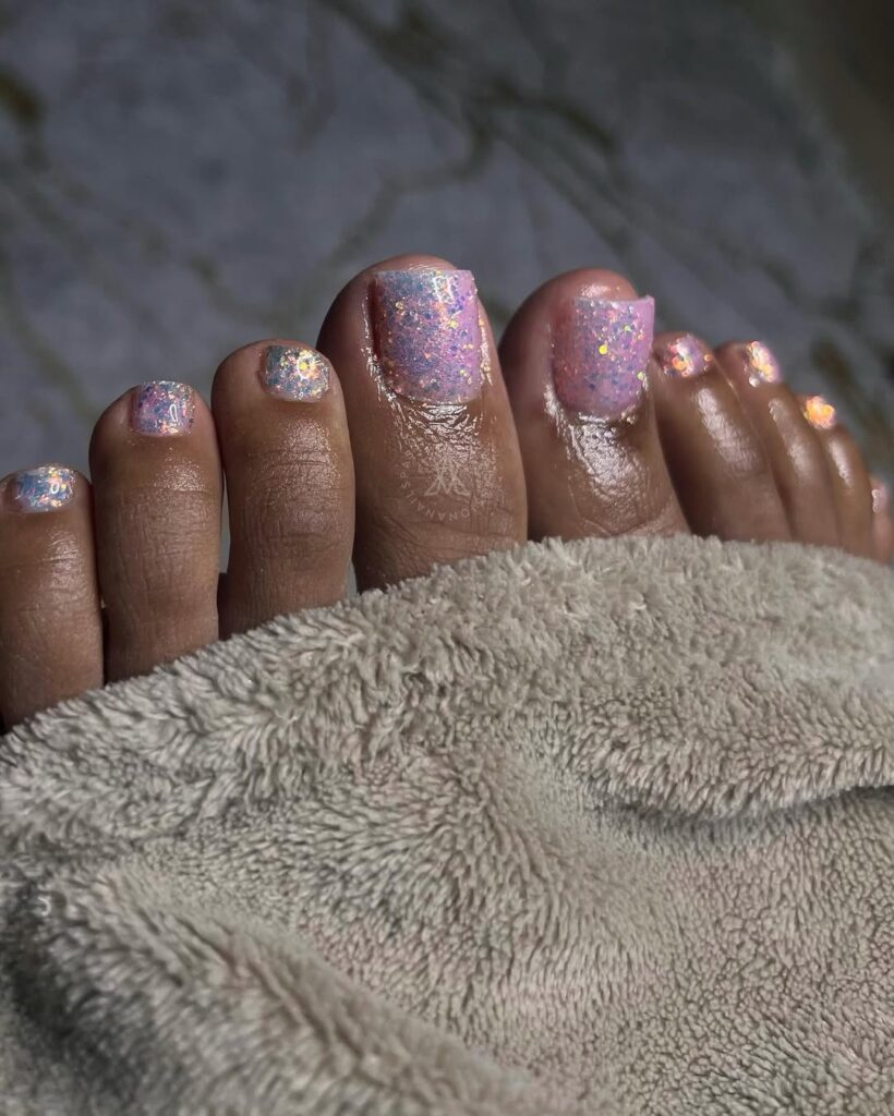 Pés de pele preta, com unha rosa-claro com brilho