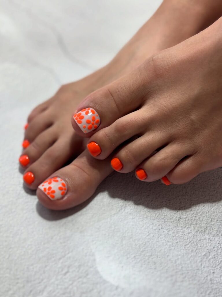 Pés de pele clara, com unha laranja decorada