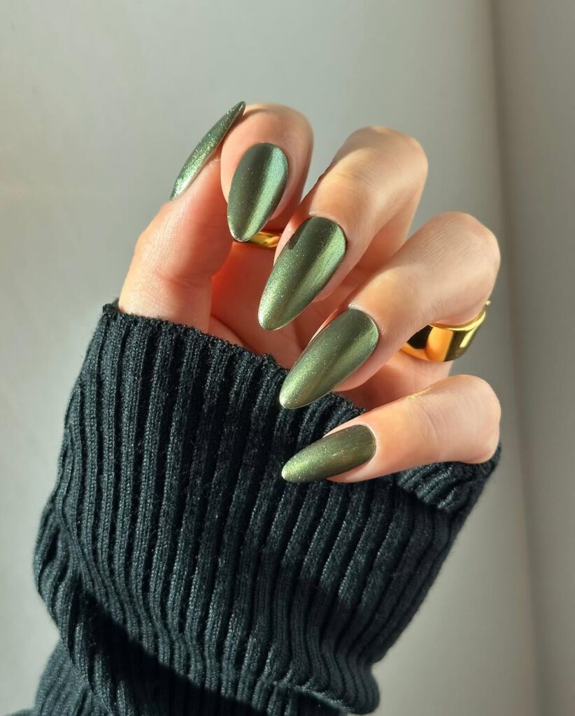 Mão de pele clara, com anéis em dourado e unha amendoada verde-musgo
