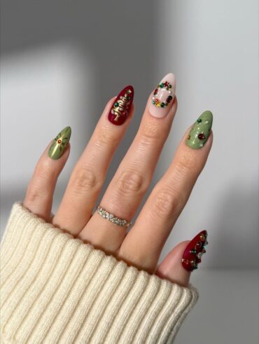 Mão de pele clara com anel de brilhantes e unha amendoada decorada para o Natal