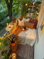 Varanda com clima de férias com almofadas, livro, luminárias e flores