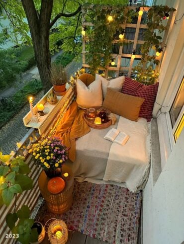 Varanda com clima de férias com almofadas, livro, luminárias e flores