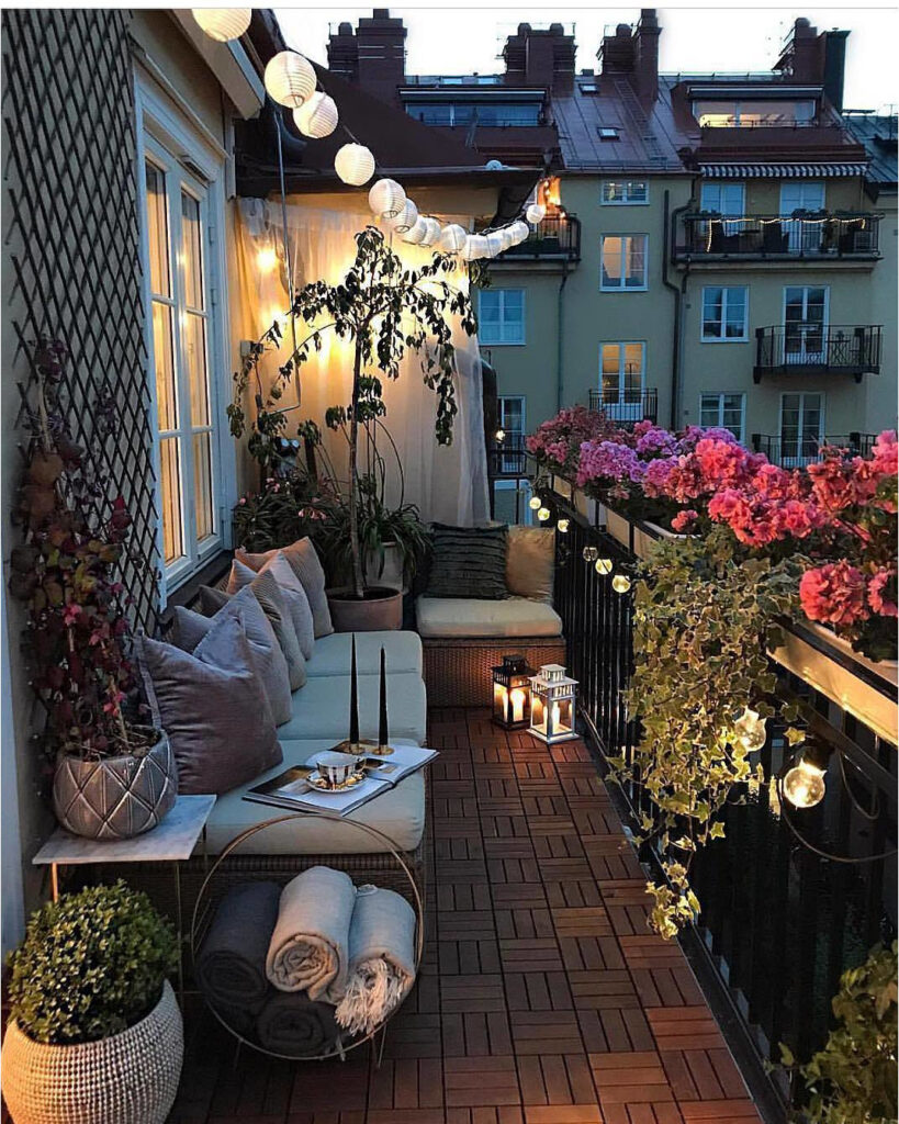 Varanda de apartamento com sofá, almofadas, plantas e luminárias japonesas