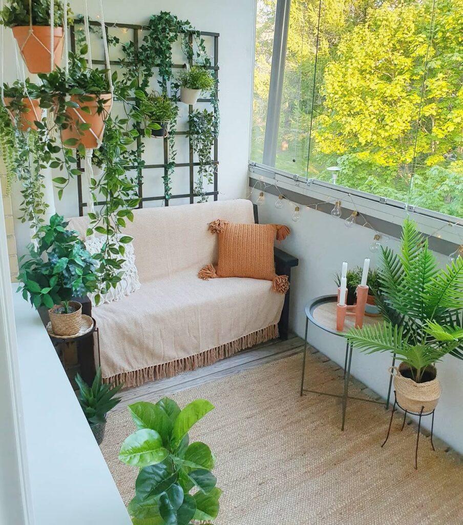 Varanda com sofá, vasos com plantas e mesinha com velas