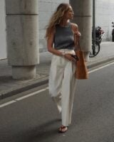Mulher jovem e magra com regata cinza, calça off-white e chinelo de dedo