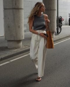 Mulher jovem e magra com regata cinza, calça off-white e chinelo de dedo