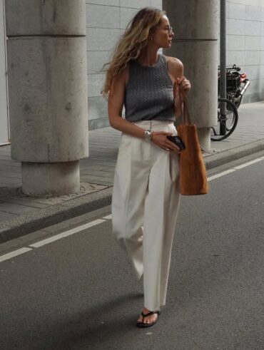 Mulher jovem e magra com regata cinza, calça off-white e chinelo de dedo