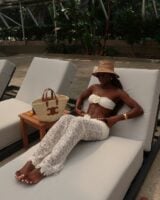 Mulher jovem usando top de biquíni branco com flor e calça de renda