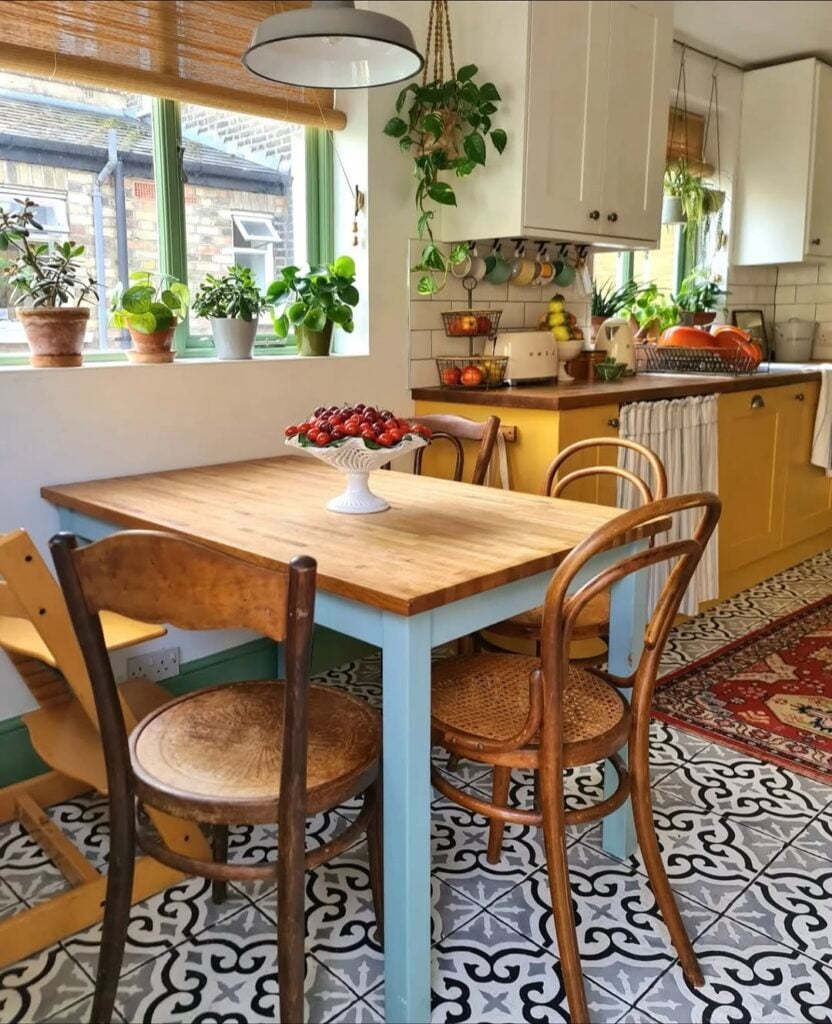 Cozinha com armário amarelo, piso colorido, mesa e cadeiras de madeira