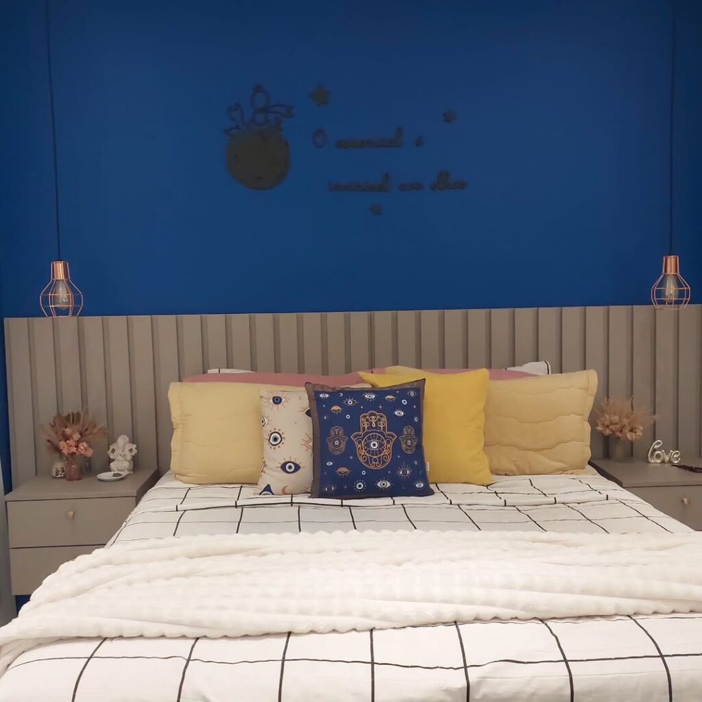 Quarto com cabeceira ripada, meia parede azul e almofadas coloridas