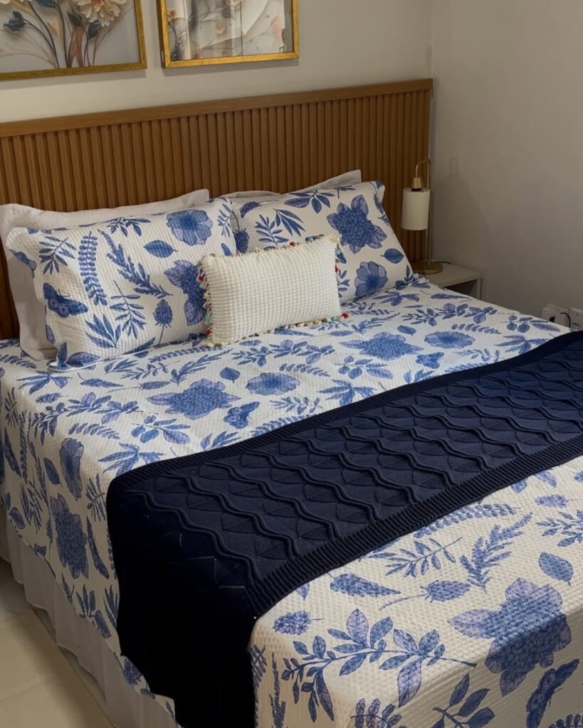 Quarto de casal com cabeceira ripada, e roupa de cama branca com flores azuis