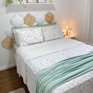 Inspiração de cama posta de verão com roupa de cama floral, e manta em tom de verde-claro