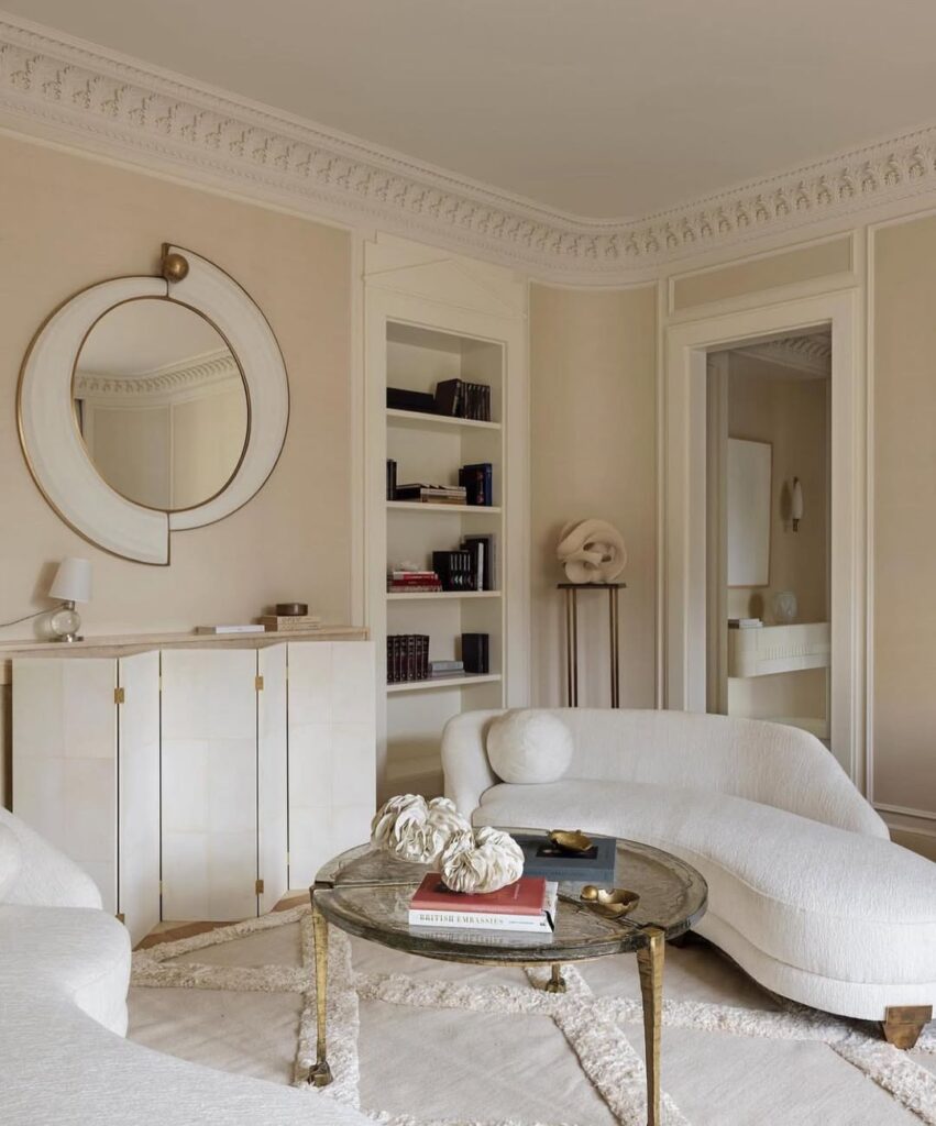 Sala em branco e bege com sofá de linhas curvas e espelho com design diferente